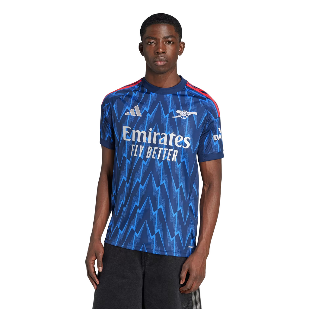 Person wearing a blue sports jersey with Adidas and Emirates branding on a white background