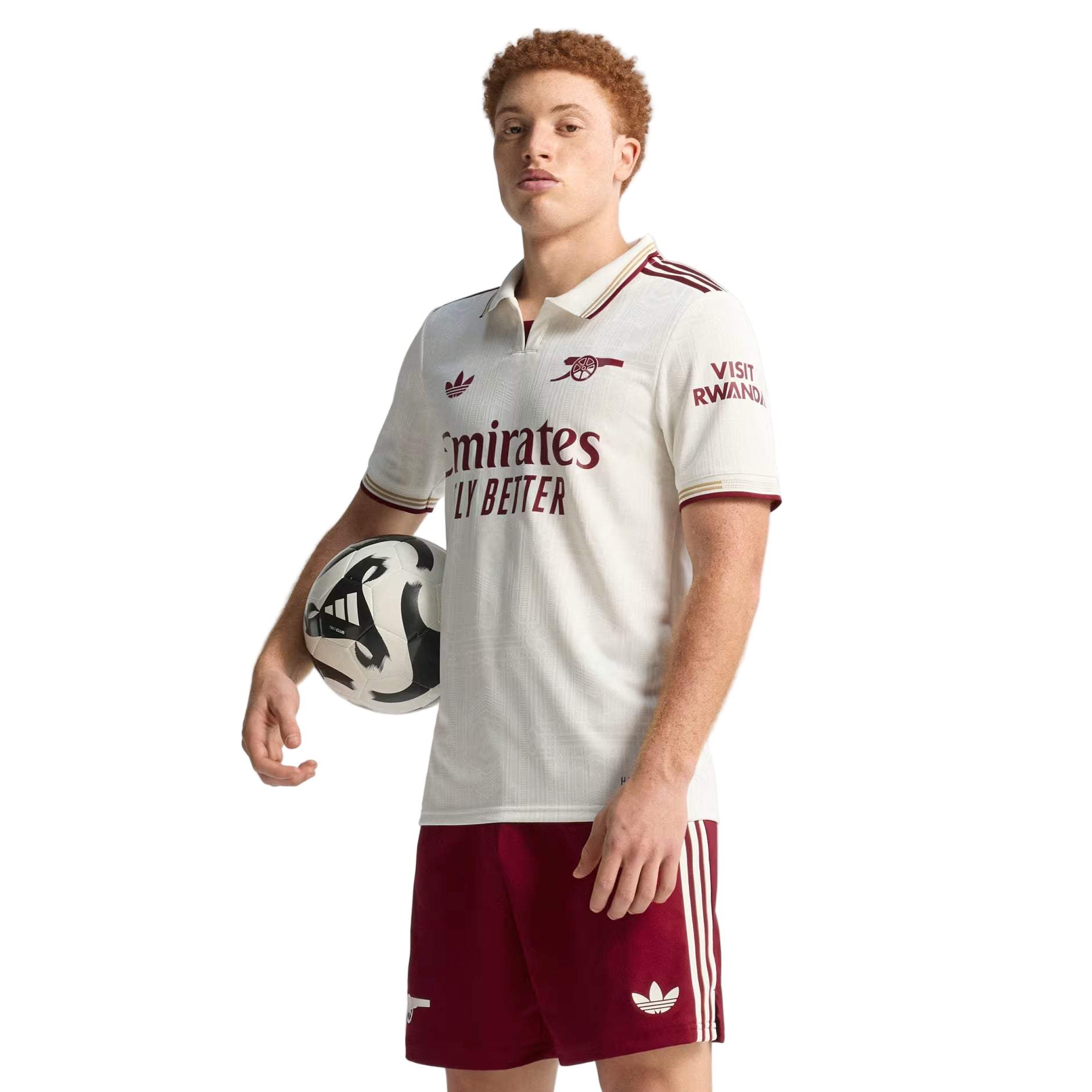 Person wearing a white sports jersey with red accents and holding a soccer ball on a plain background