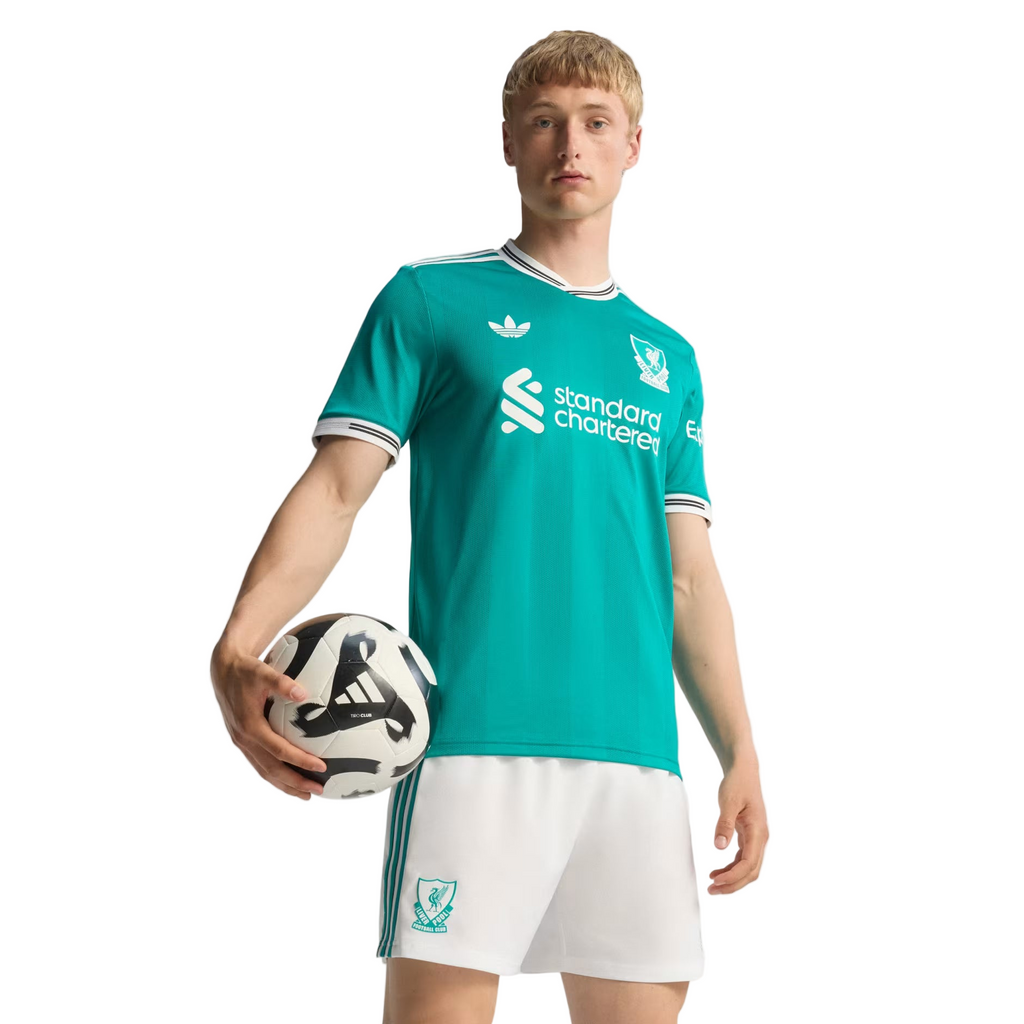 Person wearing a teal sports jersey with white shorts, holding a soccer ball on a plain background